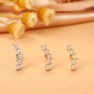 Vue macro de clous d'oreilles courbés avec zircons en argent, or et or rose poli