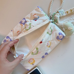 Detailed view of quilted cotton bag with cartoon print, pearl handle and green heart charm
