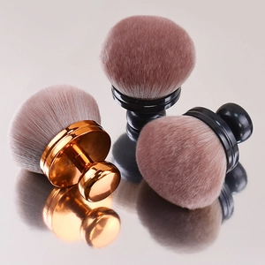 Three mushroom head powder brushes with soft bristles on a reflective surface