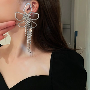 Detail of silver bow tassel ear cuff with sparkling rhinestones worn by a model
