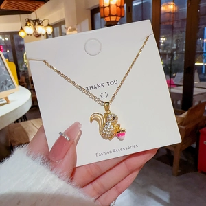 Close-up of squirrel pendant necklace with white crystals on a white jewelry card