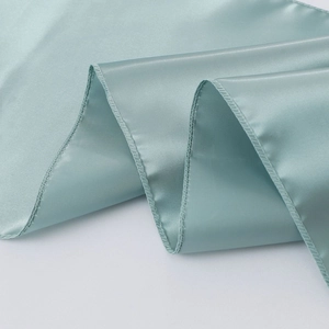 Detailed view of teal satin table runner fabric showing smooth texture and hemmed edges