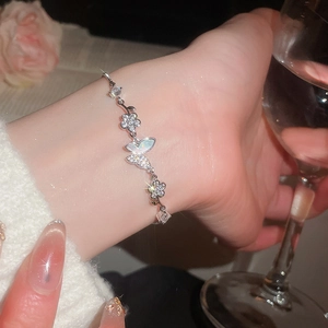 Close-up of a silver zircon flower and butterfly bracelet worn elegantly on a wrist