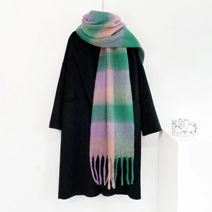 Close-up of soft mohair texture and fringe on a pink and green plaid winter scarf