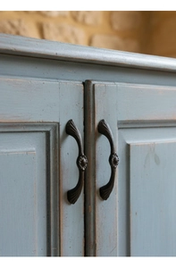 Detailed close-up of retro cast iron handle with fan-shaped decor on a blue wooden cabinet