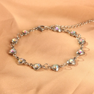 Silver stainless steel heart bracelet with rainbow zircon stones on gold satin backdrop