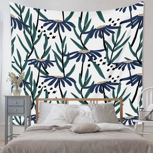 Detail of bohemian tapestry with blue floral patterns and green leaves on a white wall