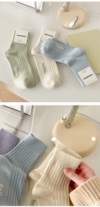 Detail of macaron-colored cotton socks with 'hello.' embroidery and wide elastic cuffs
