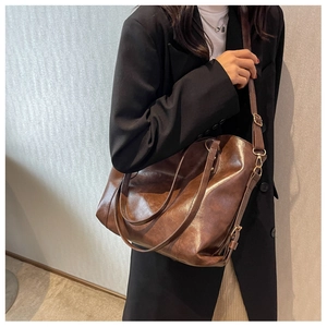 Side view of a brown leather tote bag worn by a model in a minimalist indoor setting