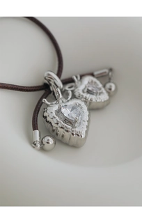 Macro shot of silver heart pendant with sparkling zircon on dark brown braided leather cord