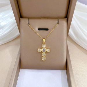 Macro shot of a gold cross pendant with clear cubic zirconia stones in a jewelry box