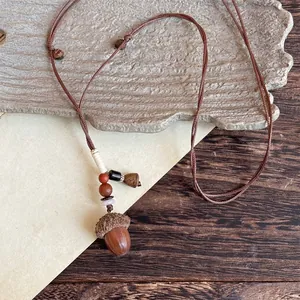 Close-up of retro acorn pendant with wood texture and red beads on brown woven cord