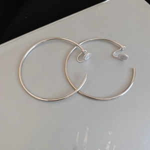 Close-up of minimalist silver hoop ear clips with clear silicone pads for non-pierced ears