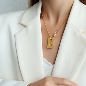 Collier à billes dorées avec pendentif lettre B et détail épingle à nourrice chic