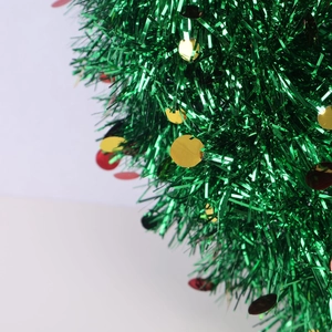 Close-up of green Christmas tinsel with festive red and gold sequins for holiday decor