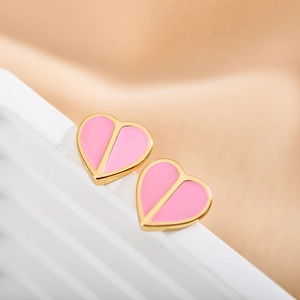 Macro shot of pink enamel heart earrings with gold trim on a soft beige display stand