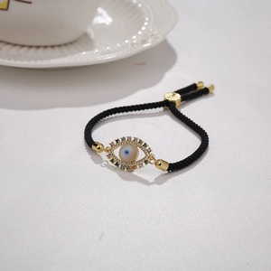 Detail showing colorful Evil Eye pendant on black braided cord with adjustable gold clasp