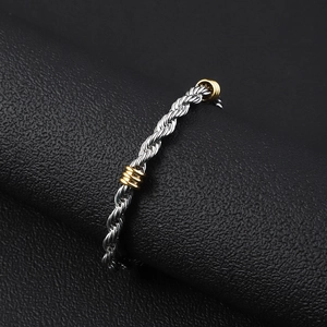 Detalle macro del anillo de cordón plateado con acentos dorados sobre cuero negro