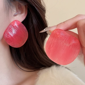 Detail of large irregular fuchsia resin earrings featuring vertical stripe textures