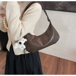 Detail of dark brown PU leather hobo bag with silver zipper and cute teddy bear charm