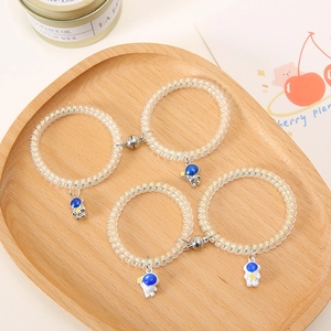 Detail of transparent coil hair ties with magnetic astronaut charms on wooden tray