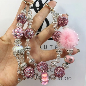 Detailed close-up of pink beaded bag charm with rhinestones, fur pompom and tassel