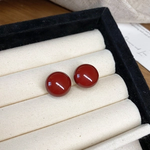 Detailansicht der roten Harzperlen-Ohrstecker auf einem cremefarbenen Schmucktablett