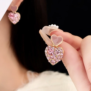 Macro shot of gold plated heart earrings with pink rhinestones and pavé setting details