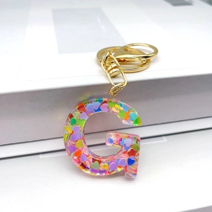 Letter G initial keychain with colorful heart sequins in transparent resin and gold clip