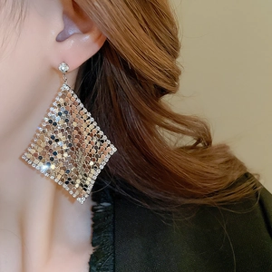 Close-up of diamond-encrusted rhombic mesh earrings worn for a luxurious fashion look