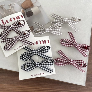 Handmade plaid bow hair clips for girls in assorted colors on a neutral background