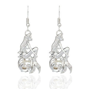 Macro view of silver mermaid drop earrings featuring a white pearl inlay detail