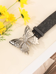 Detail of black leather belt featuring floral embossing and silver butterfly buckle