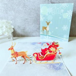 3D pop-up Christmas card featuring Santa Claus on a reindeer sleigh with festive patterns