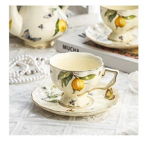 Detailed view of vintage ceramic tea set featuring lemon and butterfly motifs with gold rims