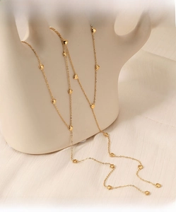 Detail einer langen Goldkette mit Herz- und Sternanhängern auf Seidenhintergrund