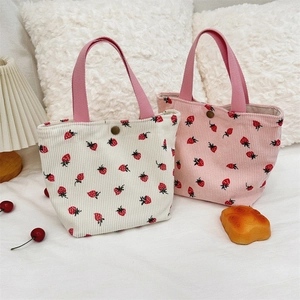 Détail du sac en velours côtelé à motif fraise avec bouton métal et poignée rose