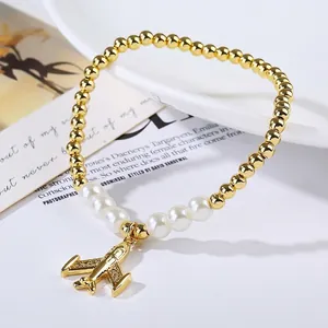 Detailed close-up of a gold bead and pearl bracelet with a sparkling airplane pendant