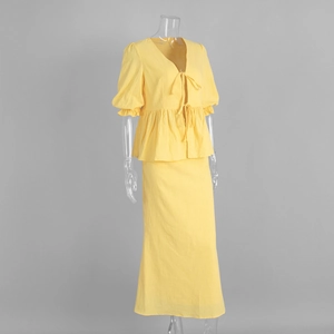 Detail of V-neck top with tie-front and ruffled hem on yellow textured fabric