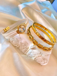 Detail of luxury white leather wrap bracelet with square crystal and gold metal bangles