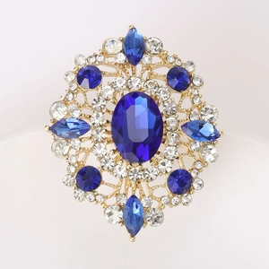 Macro shot of oval blue gemstone brooch with sparkling rhinestones in gold setting