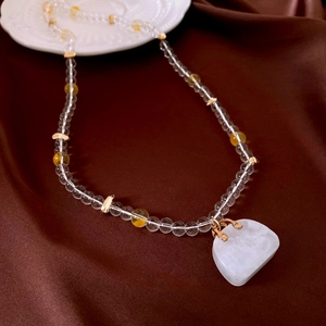 Detailed macro view of glass beaded necklace with square stone pendant on silk