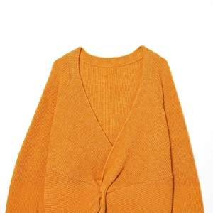 Orange long-sleeve knit sweater featuring a deep V-neck and twist detail on a white background