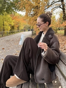 Women's faux shearling jacket with corduroy trousers and snow boots in autumn park