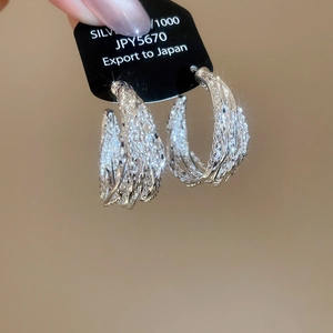 Detailed view of silver hoop earrings with intricate woven texture and pavé set zircons