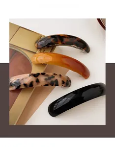 Detail view of acetate spring hair clips in tortoiseshell and leopard patterns on a book