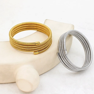 Detail of gold and silver spiral spring bracelets on elegant minimalist plaster stand