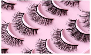 Vue macro de faux cils noirs longs et épais sur un plateau rose pour maquillage
