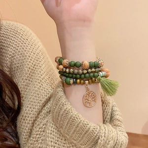 Detail of bohemian layered sandalwood beads bracelet with tree of life charm and green tassel