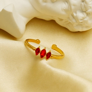Goldener verstellbarer Edelstahlring mit drei roten Markasiten auf gelbem Seidenstoff